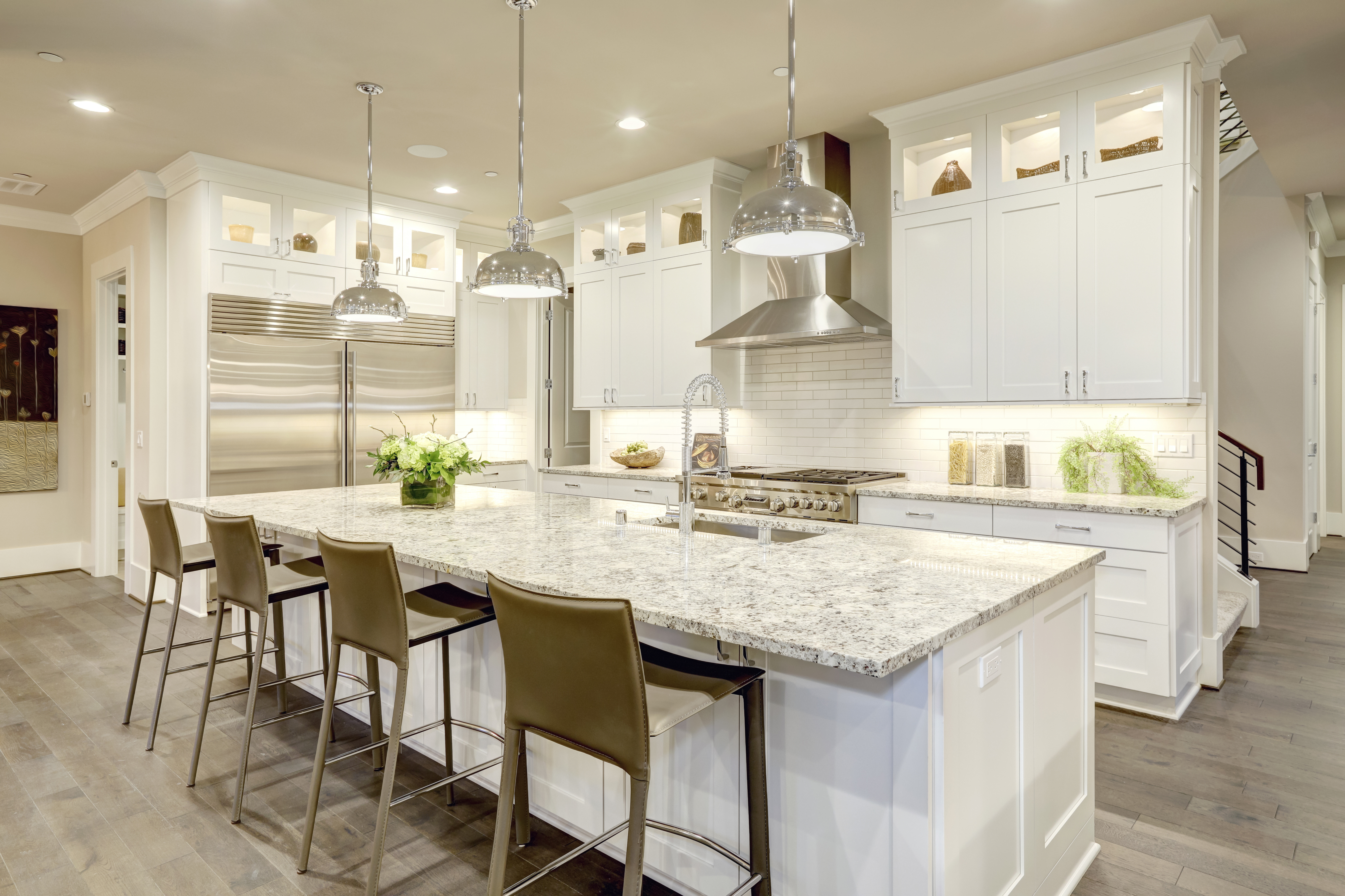 White kitchen design features large bar style kitchen island with granite countertop | Carpet Barn